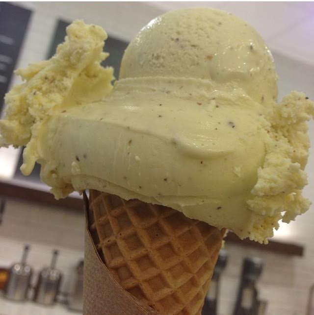 Scoops of silky olive oil ice cream with vanilla bean speckles in a waffle cone.
