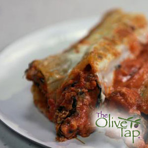 Two baked manicotti pasta shells filled with a meat mixture, topped with a red sauce served on a white plate with The Olive Tap logo in the bottom righthand corner.