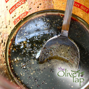 A vinaigrette with seasoning in a glass measuring cup with a spoon inside.
