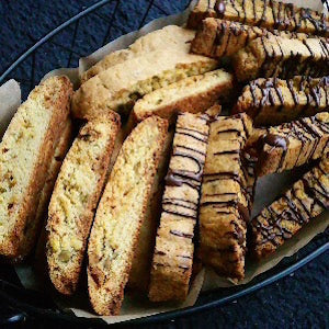 Orange pistachio biscotti arranged on a tray with half drizzled with chocolate.