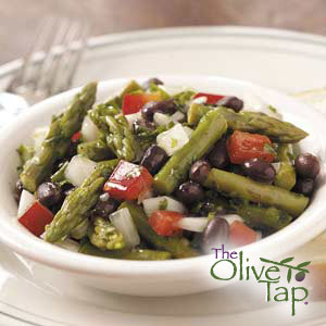 An asparagus salad with black beans, diced tomatoes, and onions served in a white bowl.