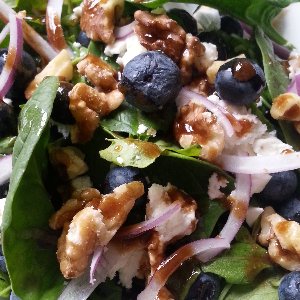 Spinach salad topped with red onions, cheese crumbles, blueberries, walnuts, and drizzled with a blueberry vinaigrette.