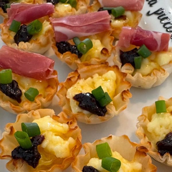 Phyllo dough shells filled with brie and topped with fig jam, green onion, and prosciutto.