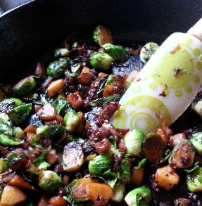 Sautéed brussels sprouts with diced prosciutto and apples cooked in a skillet.