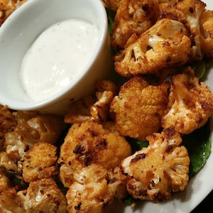 Roasted cauliflower florets served with a dipping sauce.