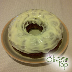 A bundt cake with lemon cream cheese icing, served on a beige plate.