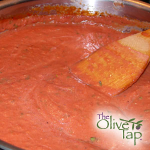 A close-up of tomato basil cream sauce in a pan with a wooden spatula.
