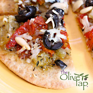 A pita bread pizza slices topped with black olives, feta cheese, onions, tomatoes, and spices.