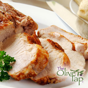 A close-up of sliced, glazed pork tenderloin served on a white plate and garnished with curly parsley.