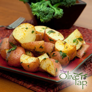 Roasted red potatoes with chopped parsley on a red dish.