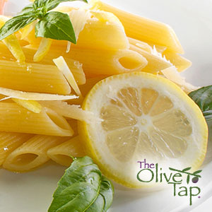 Penne pasta topped with parmesan cheese shavings and garnished with fresh basil and lemon slice served on a white plate.