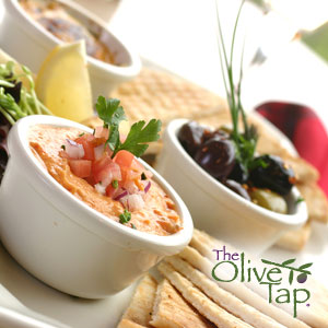 Creamy cheese dip topped with fresh tomato, onion, and cilantro on an appetizer platter served with pita bread and a lemon wedge.
