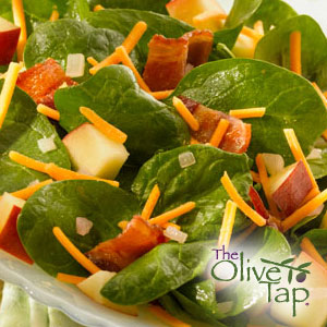 Spinach salad with apple cubes and shredded cheddar cheese.