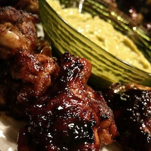 Sweet and spicy glazed chicken wings served with a bowl of avocado mango dipping sauce.