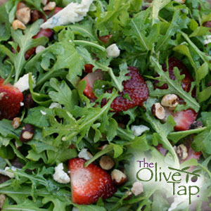 Fresh arugula salad with sliced strawberries, crumbled cheese, and chopped nuts.