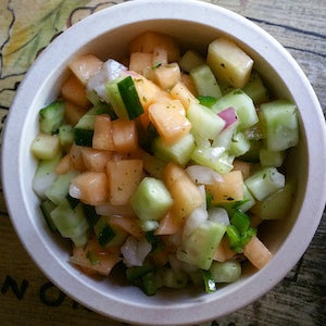 Diced melon, cucumber, red onion, and parsley served as a salsa in a white bowl.