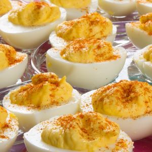 Deviled eggs arranged on a serving tray, filled with a creamy yolk mixture and sprinkled with paprika.