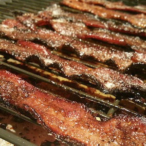 Slices of glazed bacon on a grill.