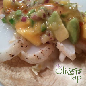 A corn tortilla topped with fresh, seasoned white fish and a mango, jalapeno, avocado, red onion salsa.