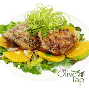 A bed of spring mix with orange slices and grilled chicken on top, as well as green sprouts for a garnish on a white plate.
