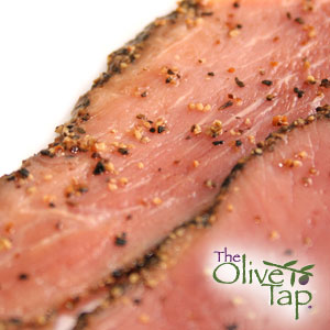 Sliced flank steak crusted with a pepper seasoning on a white background.