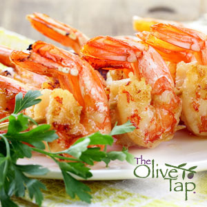 Glazed shrimp skewers on a white plate with a fresh parsley garnish.