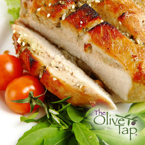 A sliced, grilled porkchop with a blood orange ginger glaze next to fresh small tomatoes and leafy greens on a white plate.