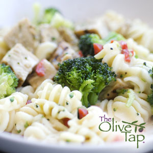 Rotini pasta tossed with broccoli florets, diced chicken, and red peppers in a light creamy dressing, served in a white bowl.