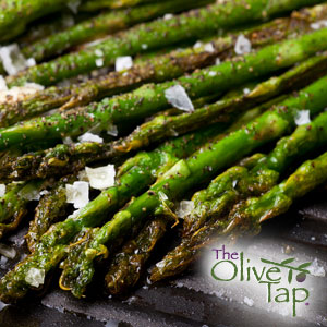 A close-up of grilled asparagus seasoned with salt and pepper and drizzled with olive oil.