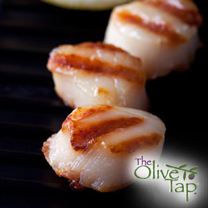 A close-up of three grilled scallops with a black background.