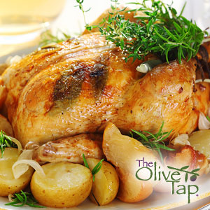 Roasted and glazed whole chicken topped with fresh herbs and served on a platter with potatoes.