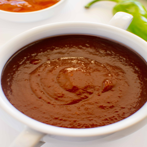 Peach balsamic barbecue sauce served in a white dish with a red rich color and creamy texture.