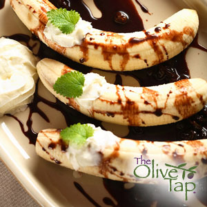 Fresh bananas topped with whipped cream, mint leaves, and dark balsamic glaze on a dessert plate. bananas for breakfast or a snack with a touch of Dark Chocolate Balsamic Vinegar! Try it for dessert too!