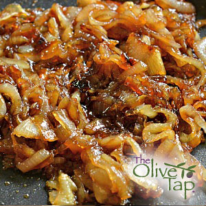 A heap of caramelized onions on a dark surface.