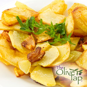 Golden fried potato slices cooked until crisp and lightly browned, garnished with fresh parsley and served on a white plate.