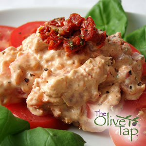 Creamy sun-dried tomato dip served over thick slices of fresh tomato and surrounded by fresh basil, topped with a spoonful of chopped sun-dried tomatoes.