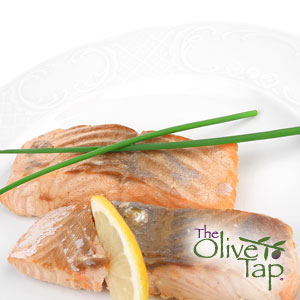Two baked salmon filets garnished with chives and the other a lemon slice, served on a white plate.