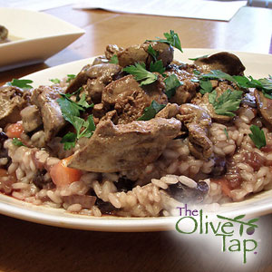 Savory mushroom risotto topped with tender sautéed chicken pieces and mushrooms, garnished with fresh parsley and served on a white plate.