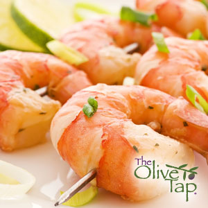Two skewers of shrimp topped with chopped green onion on a white plate with lime slices.