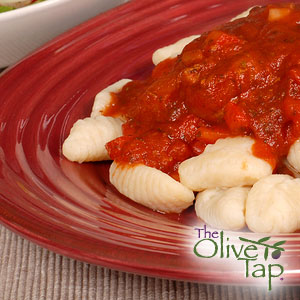 Soft potato gnocchi topped with a rich tomato sauce, served on a red plate.