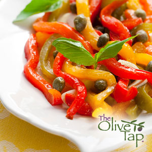 Pan-fried yellow, red, and green bell pepper slices topped with fresh basil and capers on a white plate and The Olive Tap logo on the bottom righthand side.