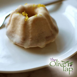 Mini glazed bundt cake topped with a smooth lemon glaze and a sprinkle of citrus zest, served on a white plate.