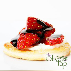A tart made from pizza dough cut into a circle with a smear of marscapone, topped with cut strawberries and drizzled with balsamic vinegar.