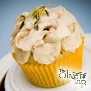 A cupcake topped with swirled balsamic whipped cream and a small herb garnish, served in a yellow cupcake liner.