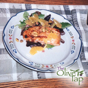 Poached salmon fillet served with a spring salad topped with oranges and nuts, served on a decorative plate.