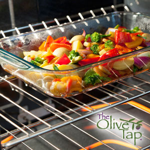 Rectangular glass dishware in an oven with red pepper, zucchini, green beans, cauliflower, and onion.