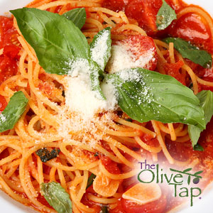 A bowl of spaghetti and red sauce with chunks of fresh garlic, topped with fresh basil leaves and grated parmesan cheese with The Olive Tap logo in the bottom righthand corner.