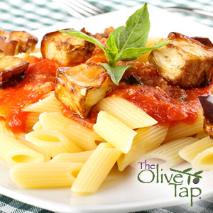 Penne pasta topped with red pasta sauce and cubes of sauteed eggplant, garnished with fresh basil on a white plate on a green and white checkered tablecloth.