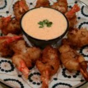 Battered shrimp surrounding a bowl of chipotle dipping sauce, served on a decorative plate.