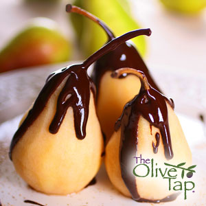 Three pears drizzled with a balsamic glaze, served on a plate with blurred pears in the background.